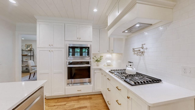 kitchen featuring decorative backsplash, light wood-type flooring, white cabinetry, light countertops, and appliances with stainless steel finishes