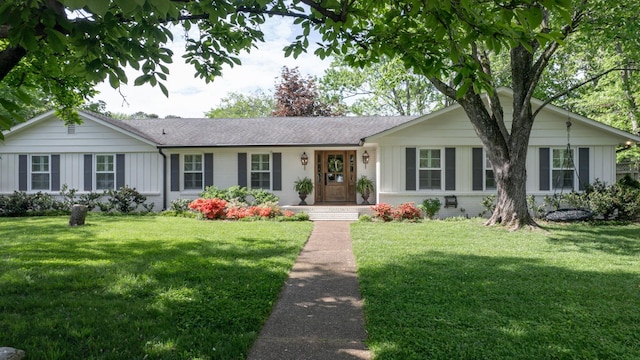 ranch-style house with board and batten siding, a front yard, and brick siding
