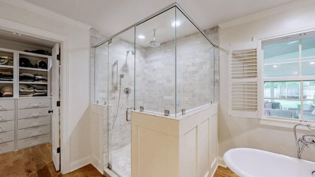 full bathroom featuring a shower stall, crown molding, baseboards, wood finished floors, and a spacious closet