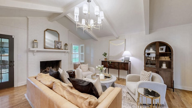 living room with lofted ceiling with beams, a notable chandelier, a fireplace, and light wood finished floors