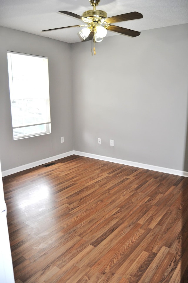 unfurnished room featuring baseboards, a ceiling fan, and dark wood-style flooring