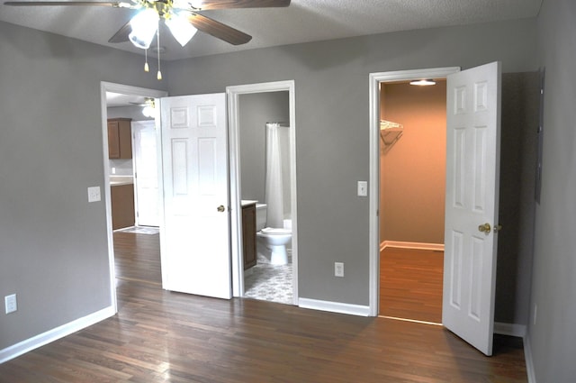 unfurnished bedroom featuring baseboards, dark wood finished floors, connected bathroom, a closet, and a walk in closet