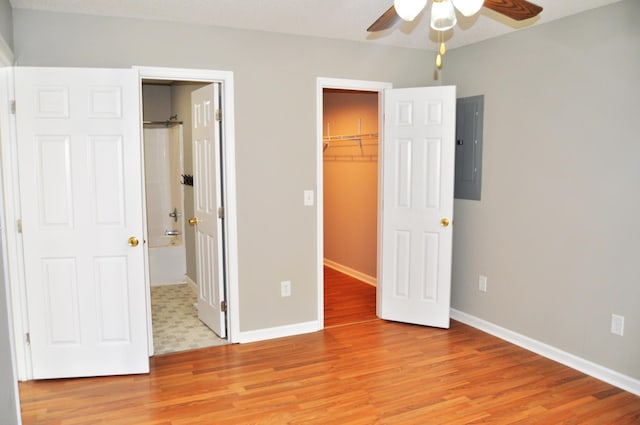 unfurnished bedroom with light wood-style floors, electric panel, baseboards, a closet, and a spacious closet