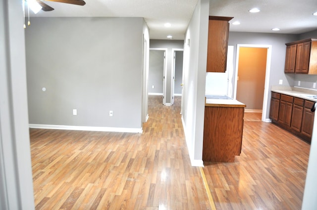 kitchen with ceiling fan, light countertops, light wood finished floors, and baseboards