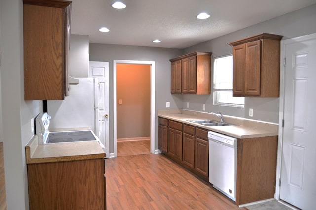 kitchen featuring recessed lighting, white appliances, light wood-style flooring, and a sink