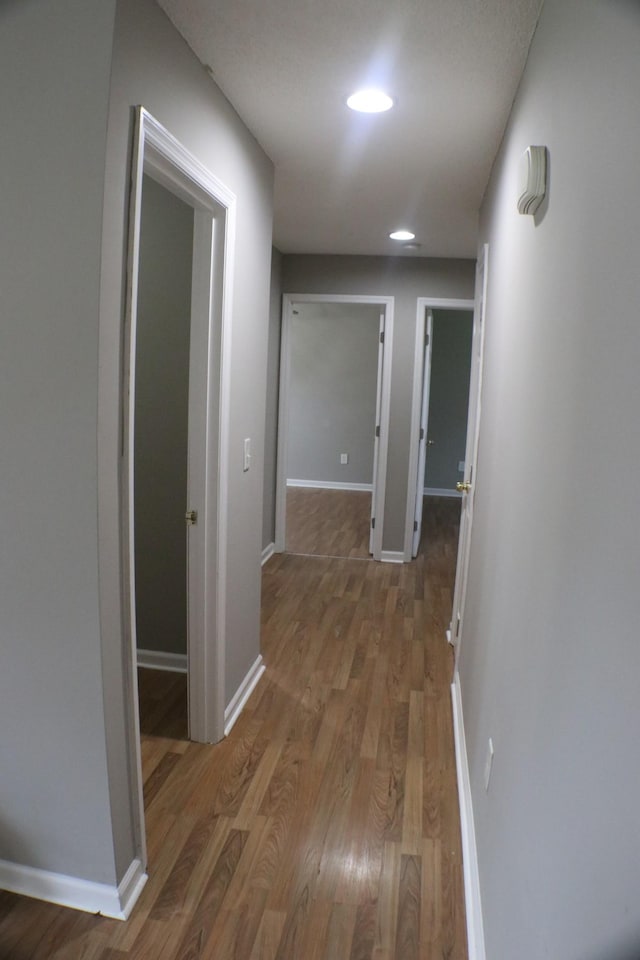 hallway with baseboards, recessed lighting, and light wood finished floors