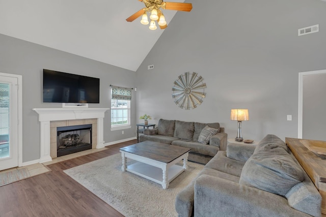 living room with visible vents, wood finished floors, baseboards, ceiling fan, and high vaulted ceiling