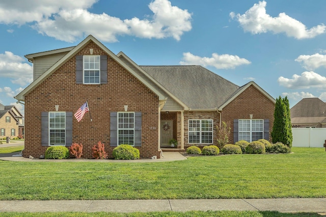 traditional home with fence, a front yard, and brick siding