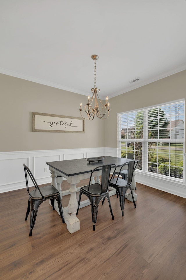 dining room with visible vents, crown molding, dark wood finished floors, a wainscoted wall, and a chandelier