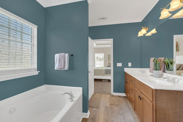 ensuite bathroom featuring crown molding, a sink, ensuite bathroom, wood finished floors, and visible vents