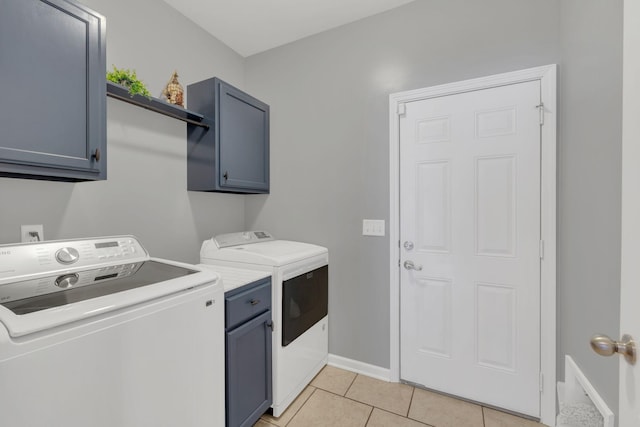 laundry area featuring baseboards, light tile patterned flooring, cabinet space, and washer and dryer