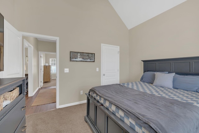 carpeted bedroom featuring baseboards and high vaulted ceiling