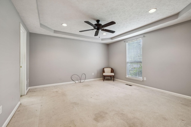 unfurnished room featuring baseboards, carpet flooring, ceiling fan, and a tray ceiling