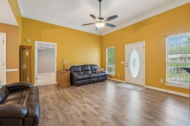 living room featuring ceiling fan, ornamental molding, and a healthy amount of sunlight