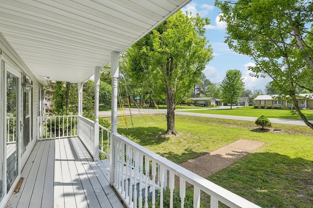 wooden terrace with a lawn and covered porch