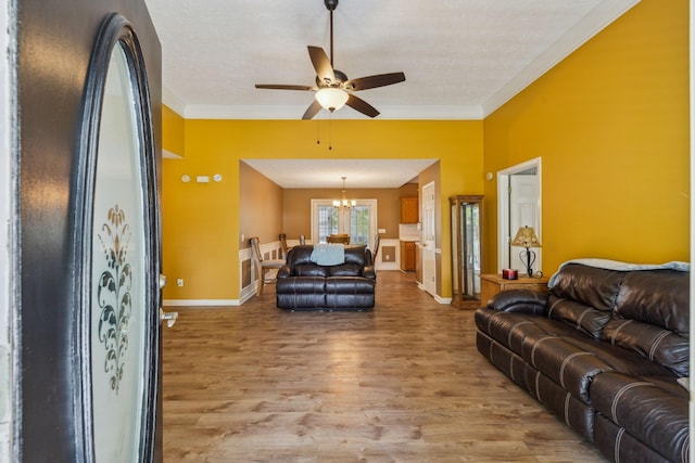 living area with crown molding, baseboards, light wood-style flooring, and ceiling fan with notable chandelier