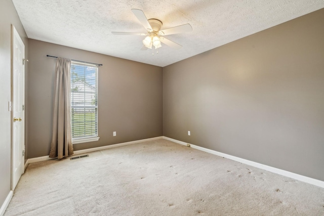 carpeted empty room with baseboards, ceiling fan, a textured ceiling, and visible vents