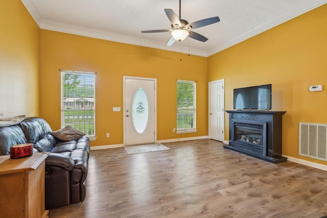 living room featuring visible vents, ornamental molding, ceiling fan, and wood finished floors