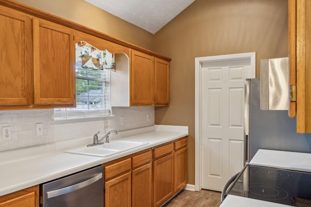 kitchen with light wood-type flooring, a sink, appliances with stainless steel finishes, and backsplash