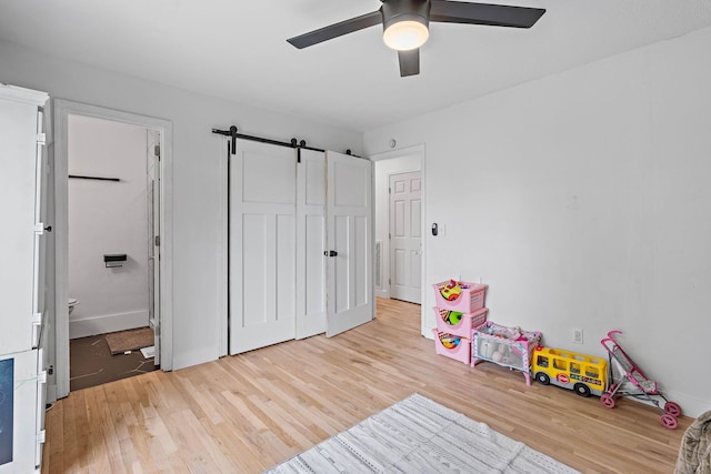 3055 Carters Creek Pike, Franklin, TN 37064 - playroom with light wood-type flooring, ceiling fan, a barn door, and baseboards