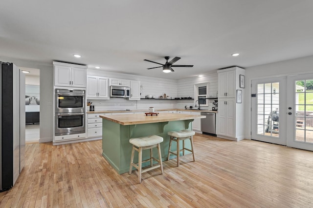 3055 Carters Creek Pike, Franklin, TN 37064 - kitchen with stainless steel appliances, butcher block counters, light wood-style flooring, a kitchen bar, and white cabinets