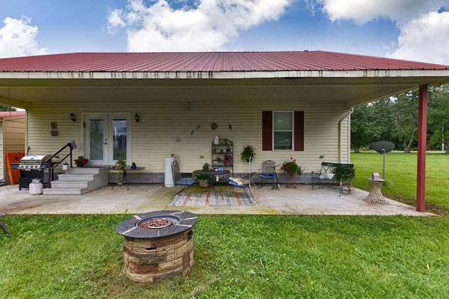 rear view of house with a patio area, metal roof, an outdoor fire pit, a lawn, and french doors