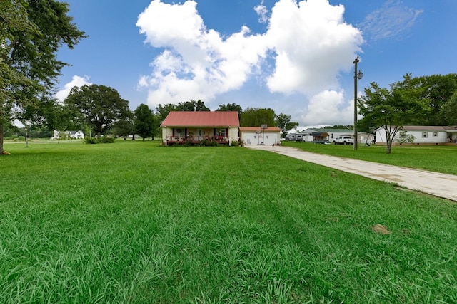 view of front of house featuring metal roof, concrete driveway, a front yard, and an attached garage
