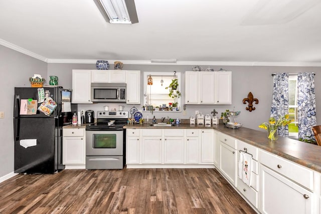kitchen with a sink, stainless steel appliances, crown molding, dark countertops, and white cabinets