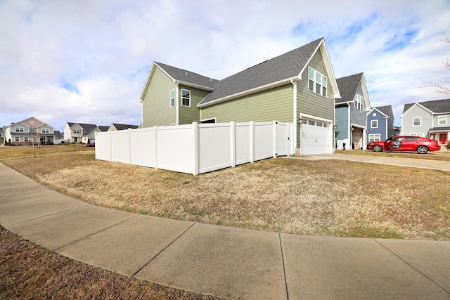 view of home's exterior with fence, a garage, a residential view, roof with shingles, and concrete driveway