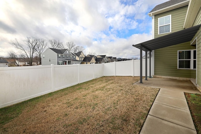 view of yard featuring a patio, a fenced backyard, and a residential view
