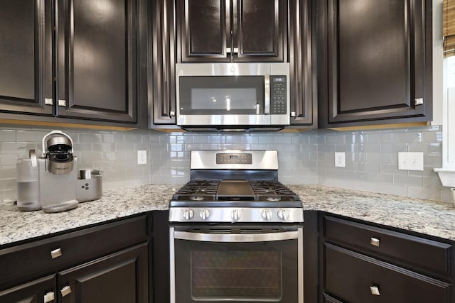 kitchen featuring light stone counters, dark brown cabinets, stainless steel appliances, and decorative backsplash