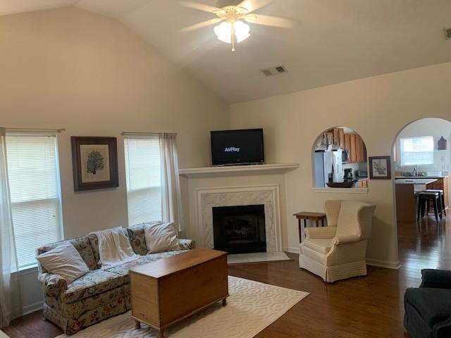 living area featuring ceiling fan, wood finished floors, lofted ceiling, and a healthy amount of sunlight