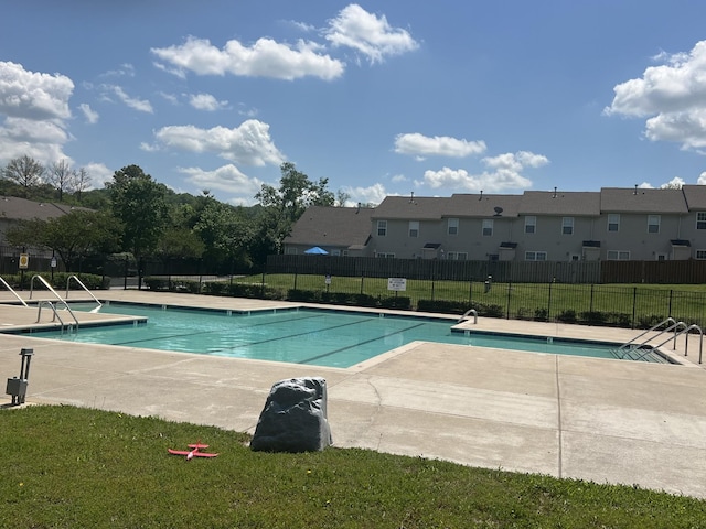 pool featuring a lawn, fence, a patio, and a residential view