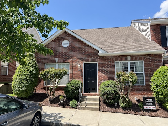 view of front of home with roof with shingles and brick siding