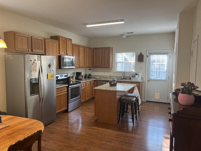 1101 Downs Blvd Unit K101, Franklin, TN 37064 - kitchen with stainless steel appliances, a breakfast bar area, dark wood-type flooring, a kitchen island, and brown cabinetry