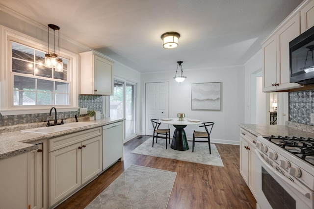 kitchen with a sink, dark wood-type flooring, tasteful backsplash, white appliances, and ornamental molding