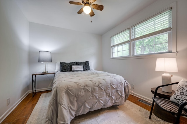 bedroom featuring wood finished floors, visible vents, a ceiling fan, and baseboards