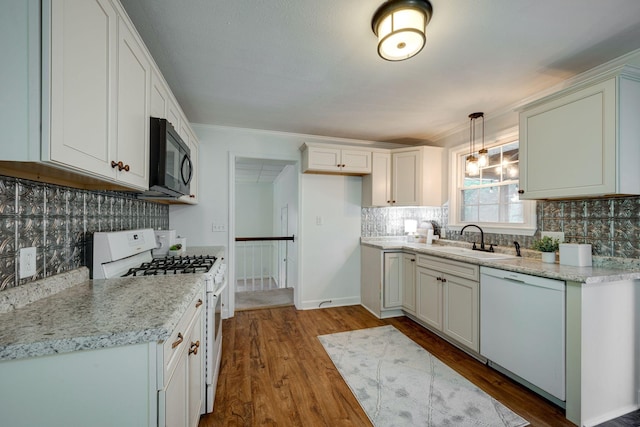kitchen with wood finished floors, white appliances, decorative backsplash, and a sink