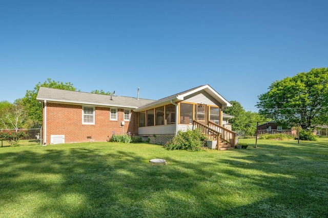 back of house featuring a sunroom, a lawn, brick siding, and fence