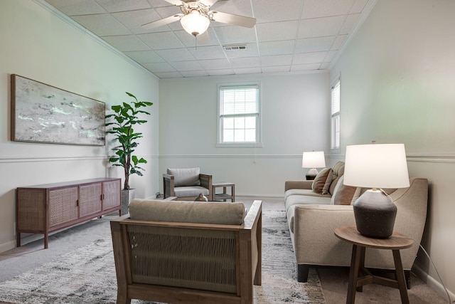 living area featuring a ceiling fan, visible vents, a drop ceiling, and carpet