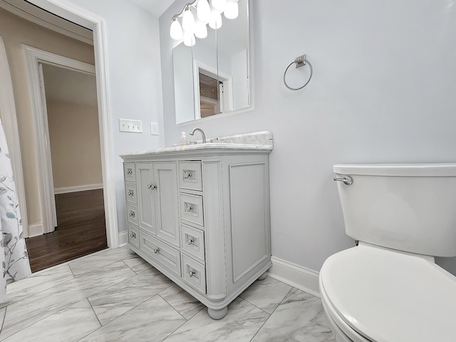 bathroom with baseboards, toilet, vanity, and marble finish floor
