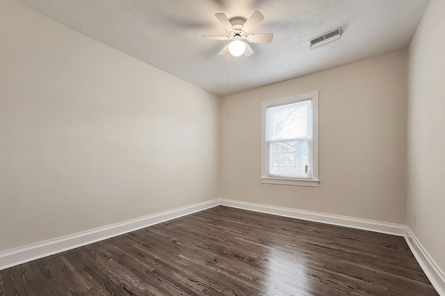 empty room featuring visible vents, a ceiling fan, dark wood-style floors, and baseboards