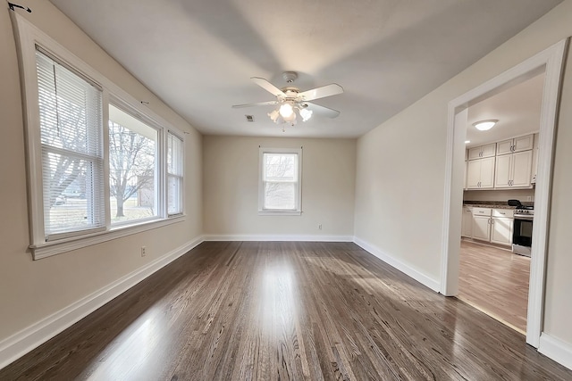 empty room featuring dark wood finished floors, baseboards, visible vents, and ceiling fan