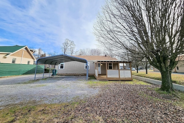 view of front of house with driveway, fence, a carport, and a wooden deck