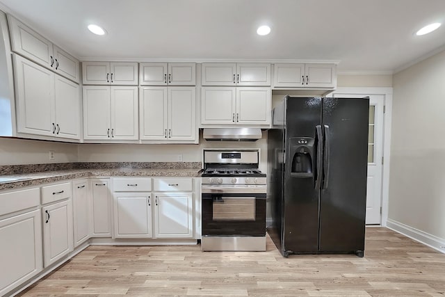 kitchen featuring under cabinet range hood, black fridge, light wood-style flooring, ornamental molding, and stainless steel gas range oven