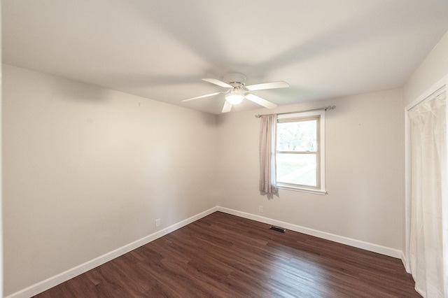 unfurnished bedroom featuring baseboards, ceiling fan, dark wood-type flooring, and visible vents