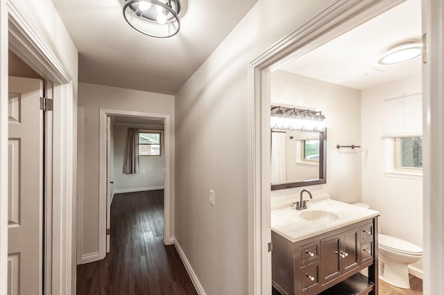 hallway featuring baseboards, a sink, and dark wood-style floors