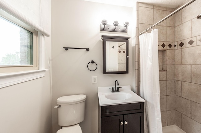 bathroom with toilet, a tile shower, and vanity