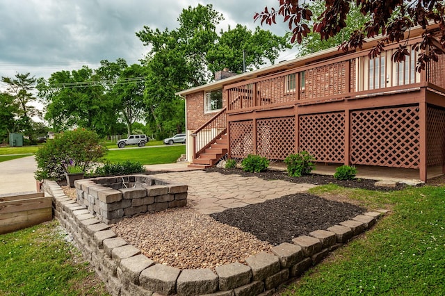 view of yard with stairs, an outdoor fire pit, a wooden deck, and a patio