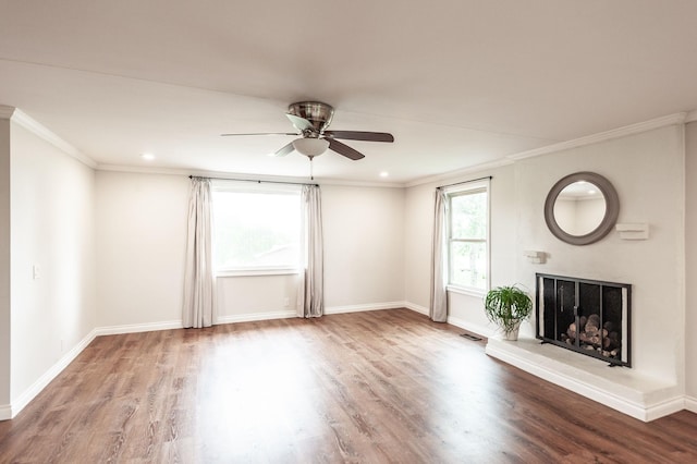 unfurnished living room with crown molding, visible vents, wood finished floors, baseboards, and ceiling fan